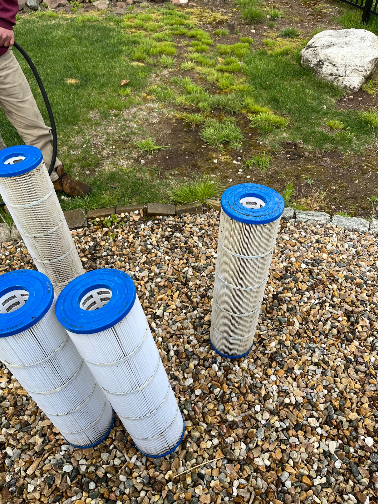 Pool cartridge filters standing upright on gravel ready for cleaning service