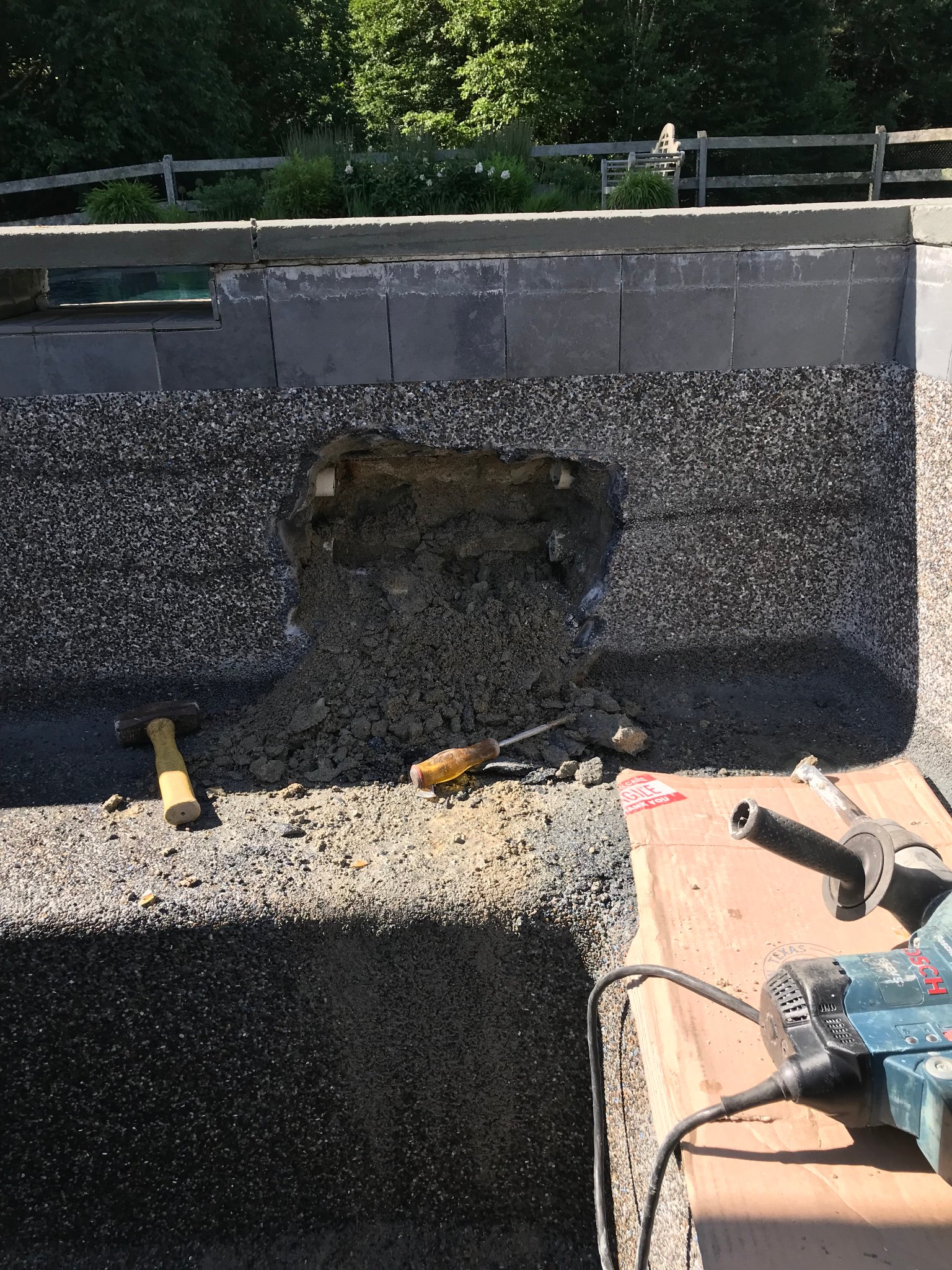 Spa wall chiseled open to access failed plumbing behind the shell — spa leak repair