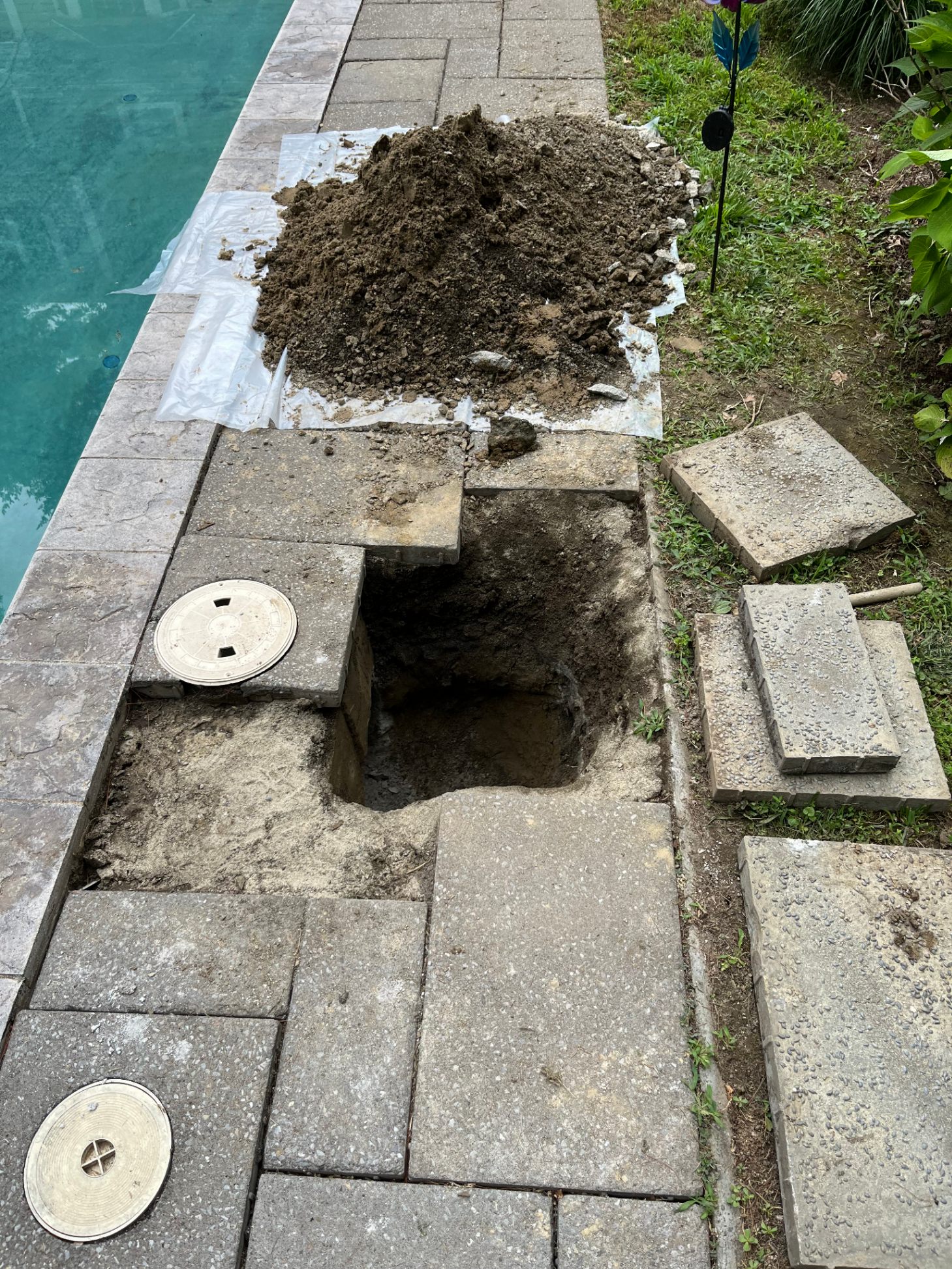 Excavated pool deck with pavers removed exposing underground pipe access for leak repair