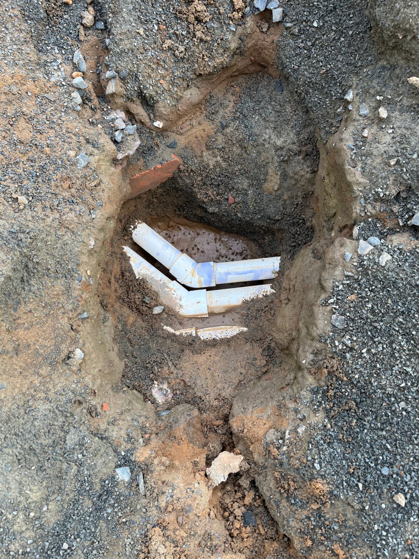 Excavated pool plumbing showing cracked PVC fitting — leak repair in progress