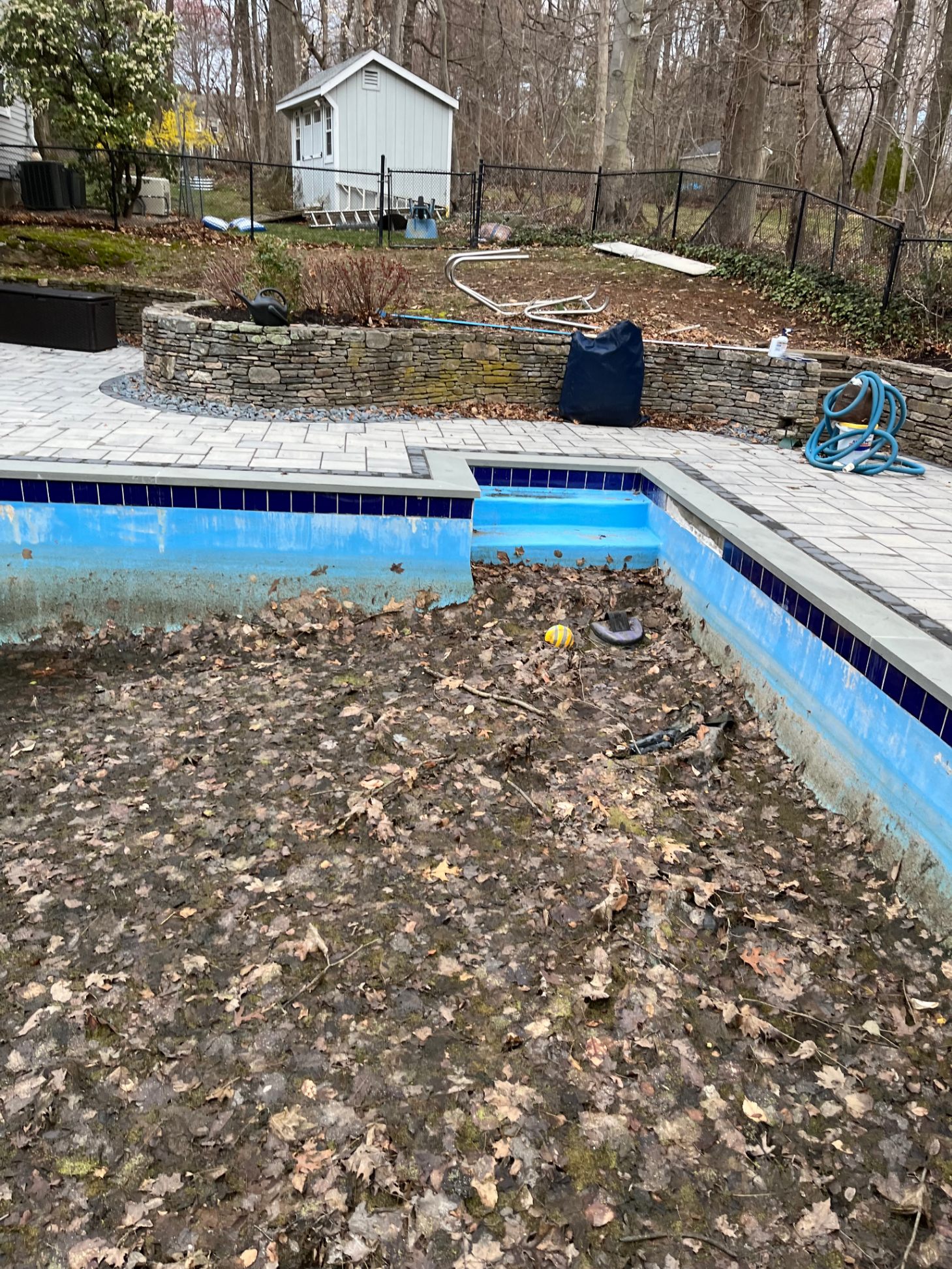 Drained residential pool filled with leaves and debris before spring opening service